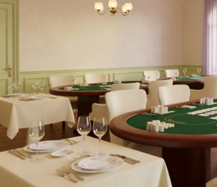 Card lounge aux tons crème et pistache avec tables de poker et assises confortables dans un restaurant.